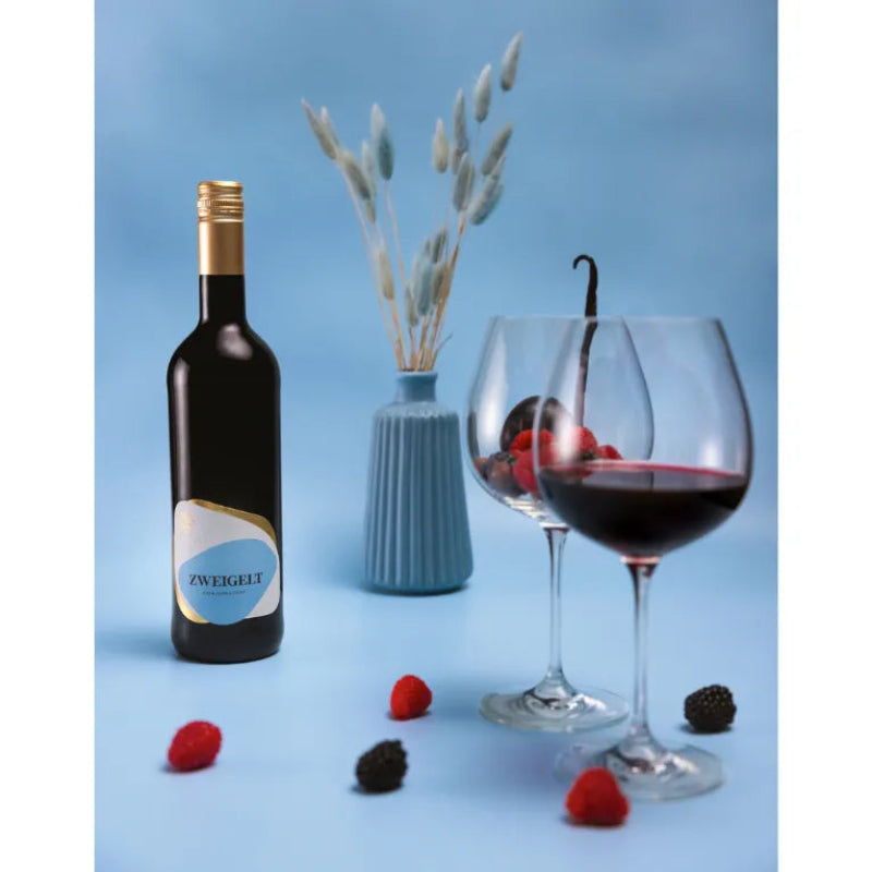 Wine bottle with a label, two wine glasses filled with red wine, and berries on a blue background